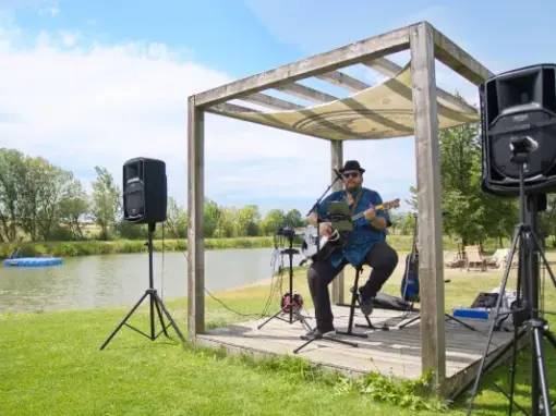 Musiker mit Gitarre, Teich im Hintergrund
